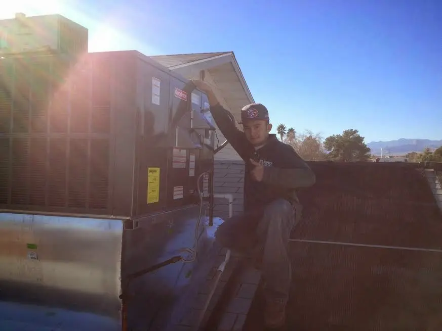 HVAC technician performing Air Duct Cleaning on a rooftop unit in Hemet